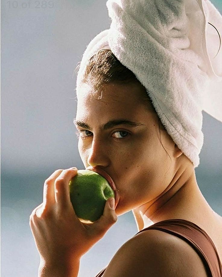 Woman with towel holding green apple.