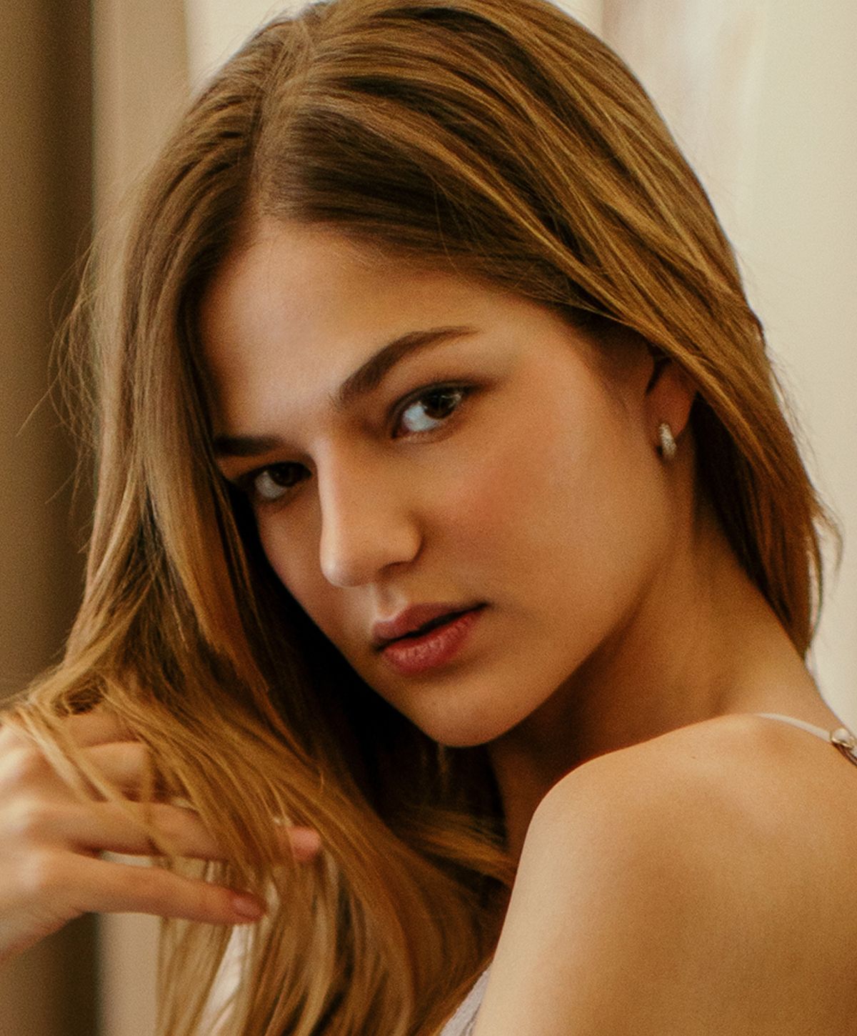 Woman with stylish earrings and soft expression.