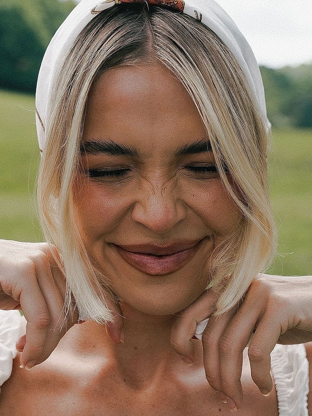 Smiling woman with blonde hair and headscarf.