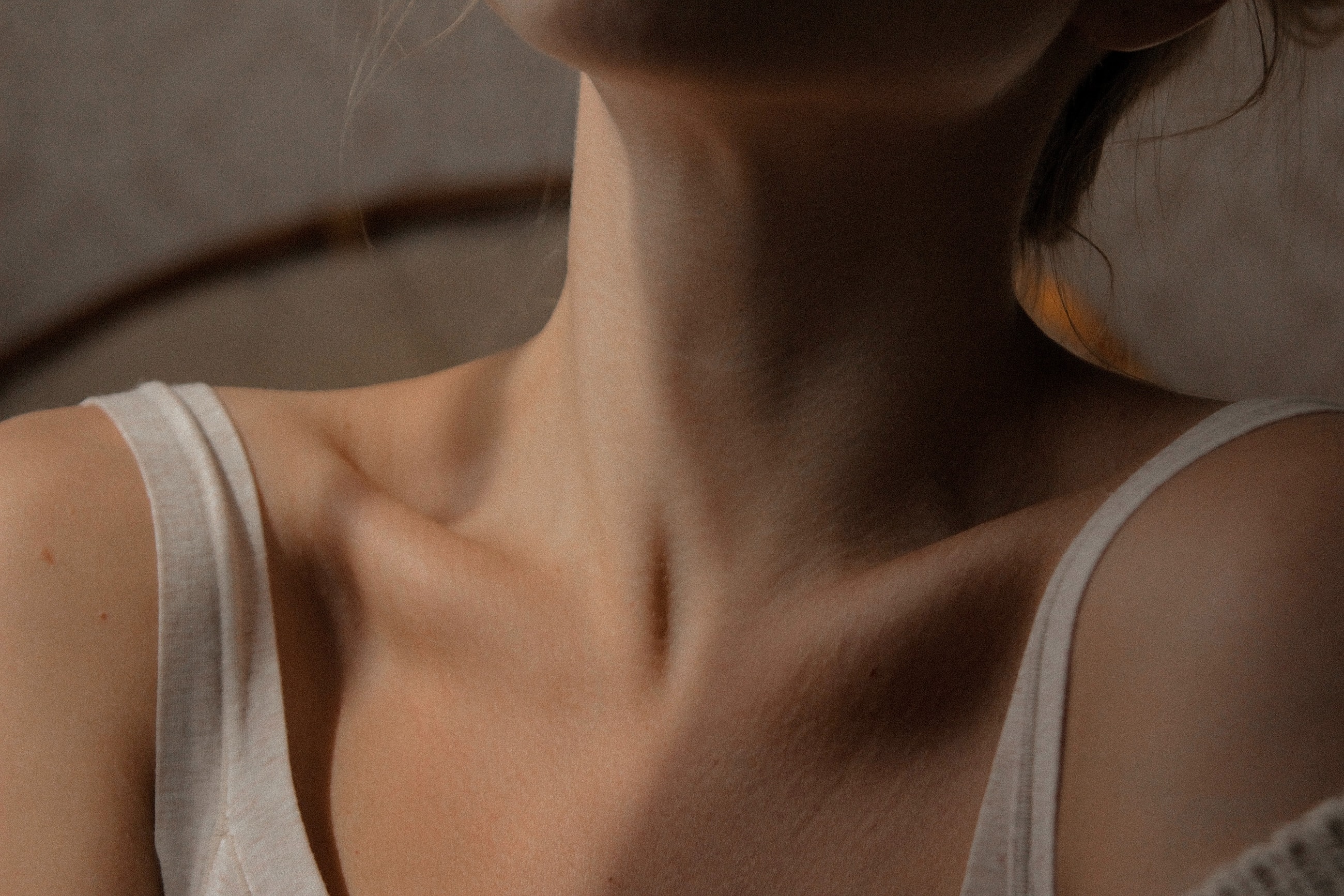 Person's neck and shoulder in soft lighting.