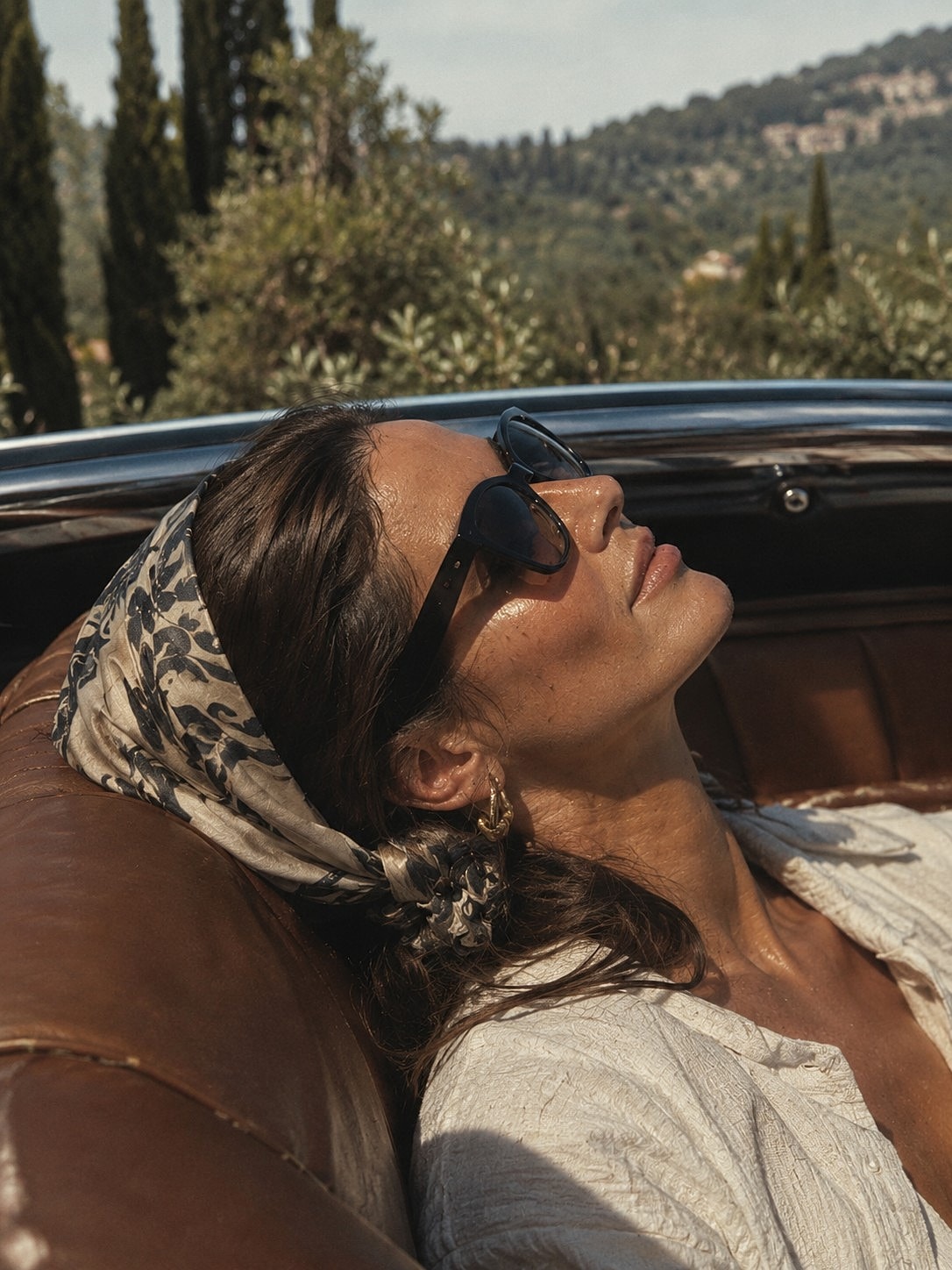 Woman relaxing in vintage car, sunglasses on.