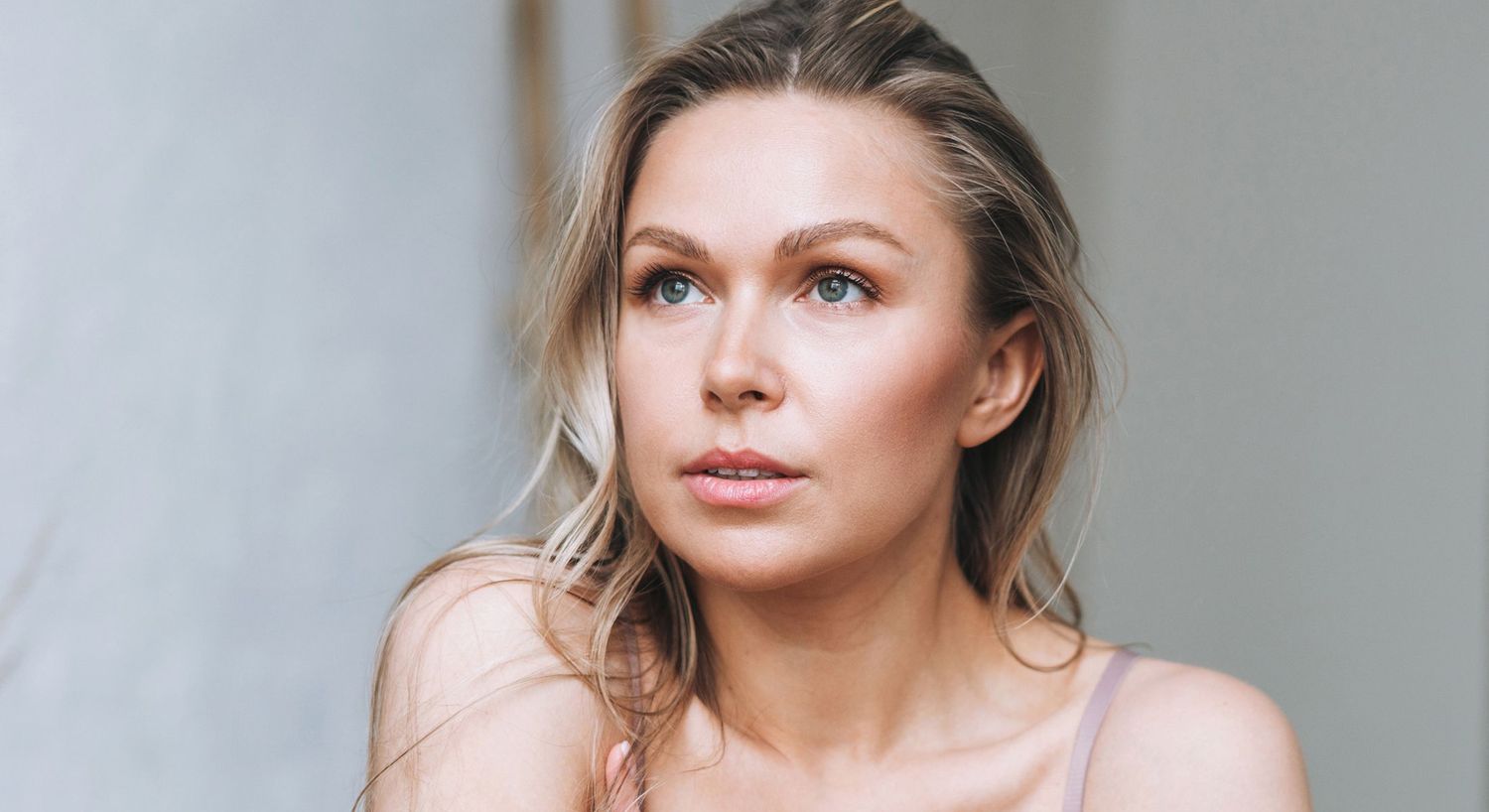 Woman with long hair looking thoughtfully into distance.