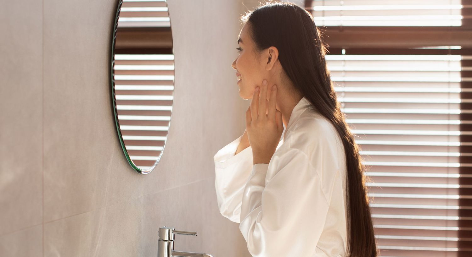 Woman in bathrobe admiring reflection in mirror.